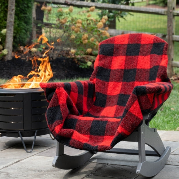 Red and black checkered Chair Blanket draped over a gray rocking chair by a fire pit.